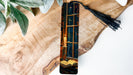 a wooden piece of art with a tassel hanging from it