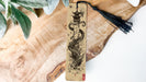 a bookmark with a dragon on it sitting on a piece of wood