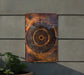 a metal art piece hanging on the side of a building