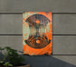 an orange and black sign on a wall next to a potted plant