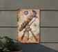 a metal sign with a telescope on it
