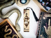 a bookmark with a snake and a lamp on it