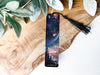 a bookmark sitting on top of a wooden table next to a plant