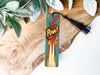 a wooden piece of art with a tassel on top of it