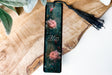 a bookmark with flowers and a tassel on a wooden table