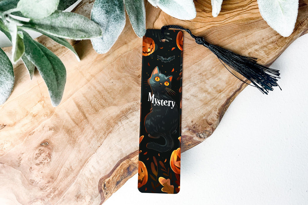 a bookmark with a black cat and pumpkins on it