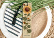 a bookmark with a sunflower on it sitting on a plate