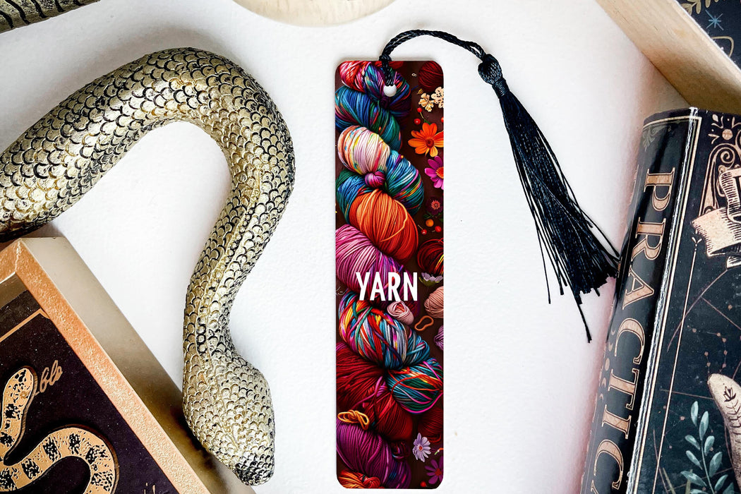 a bookmark with yarn and a snake next to it