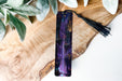 a purple bookmark with a tassel on top of it