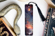 a bookmark with a painting of a sunset and a snake