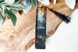 a bookmark sitting on top of a wooden table next to a plant