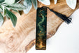 a bookmark sitting on top of a wooden table next to a plant