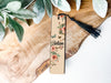 a bookmark sitting on top of a wooden table next to a plant