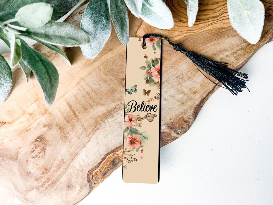 a bookmark sitting on top of a wooden table next to a plant