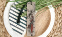 a white plate topped with a bookmark next to a plant