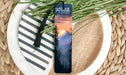 a bookmark sitting on top of a plate next to a plant