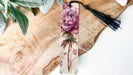 a bookmark with a flower and a tassel hanging from it