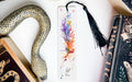 a bookmark with a feather and a snake on it