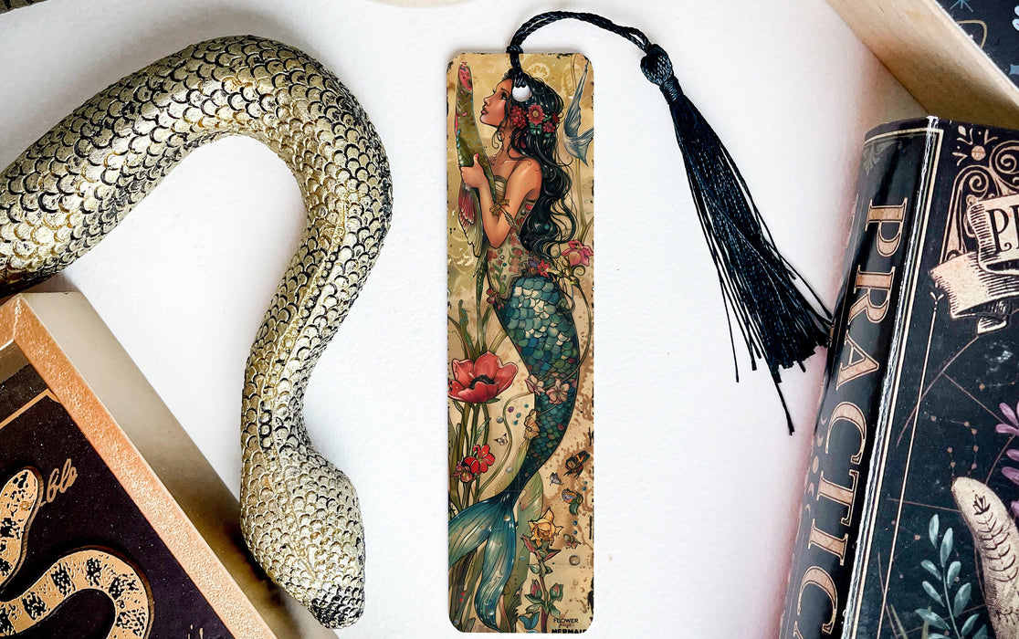a bookmark with a mermaid on it next to books