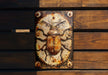 a metal clock with a bug on it on a wooden bench