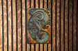 a metal art piece hanging on a wooden wall