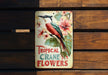a metal sign with a bird and flowers on it