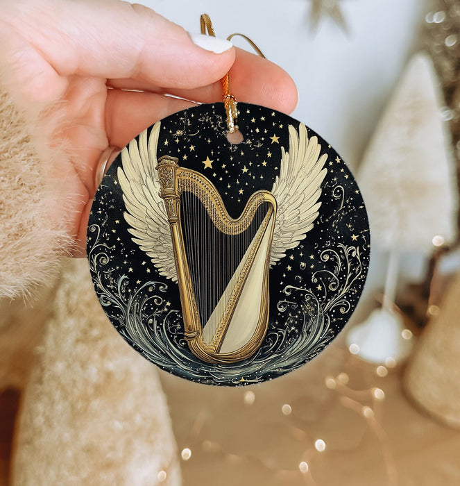 a hand holding a christmas ornament with a golden harp