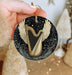 a hand holding a christmas ornament with a golden harp