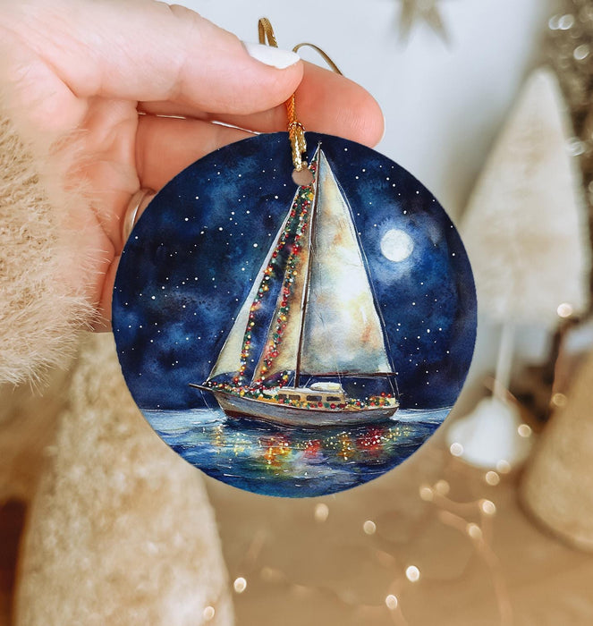 a hand holding a christmas ornament with a sailboat on it