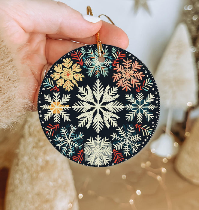 a hand holding a christmas ornament with snowflakes on it