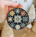 a hand holding a christmas ornament with snowflakes on it