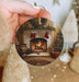 a person holding a christmas ornament with a fireplace in the background
