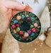 a hand holding a christmas ornament decorated with balls of yarn