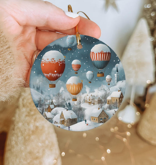 a hand holding a christmas ornament with hot air balloons