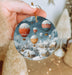 a hand holding a christmas ornament with hot air balloons