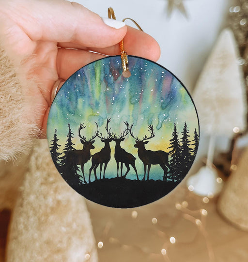 a hand holding a christmas ornament with two deers