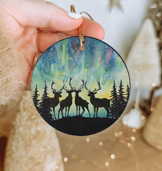a hand holding a christmas ornament with two deers