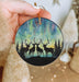 a hand holding a christmas ornament with two deers
