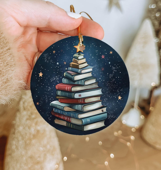 a hand holding a christmas ornament with a christmas tree made of books