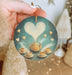 a hand holding a ceramic ornament with a painting of a teapot and
