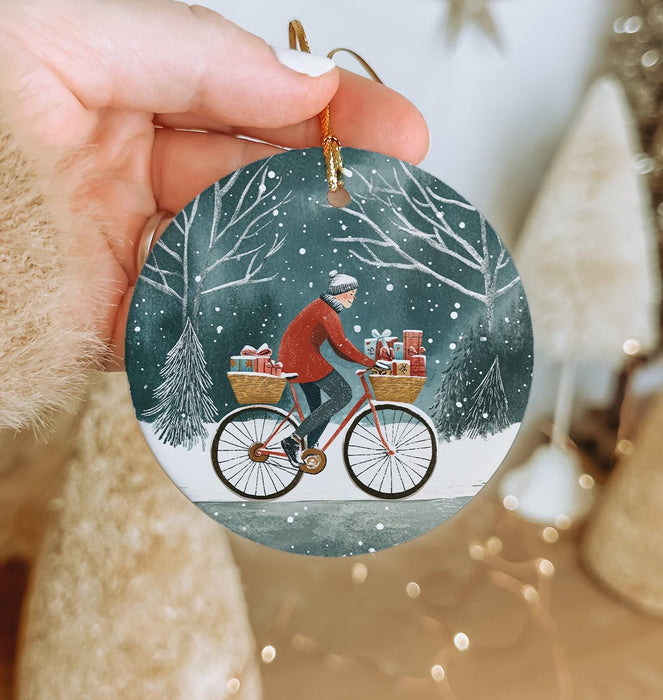 a hand holding a christmas ornament with a man riding a bike