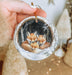 a hand holding a christmas ornament with two foxes