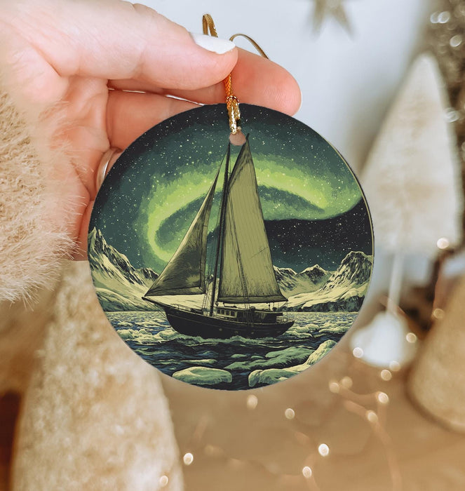 a person holding a christmas ornament with a sailboat on it
