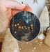 a person holding a christmas ornament with a house on it