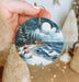 a person holding a christmas ornament in their hand
