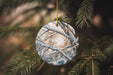 a glass ornament hanging from a pine tree
