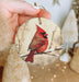 a hand holding a christmas ornament with a cardinal on it