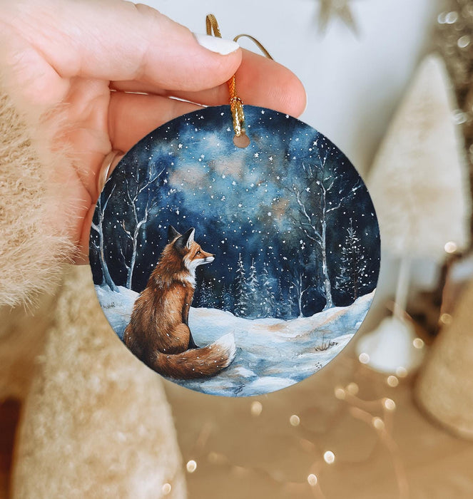a hand holding a christmas ornament with a fox on it