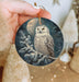 a person holding a christmas ornament with an owl on it