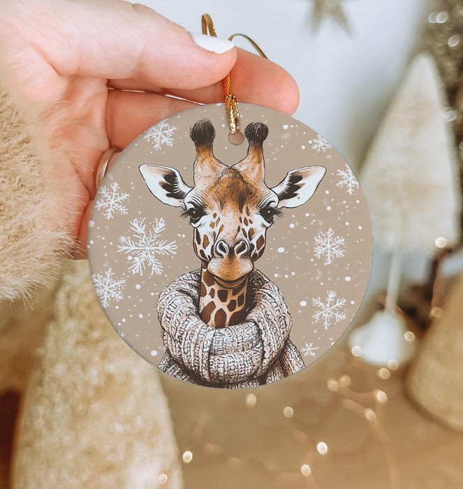 a hand holding a christmas ornament with a picture of a giraffe
